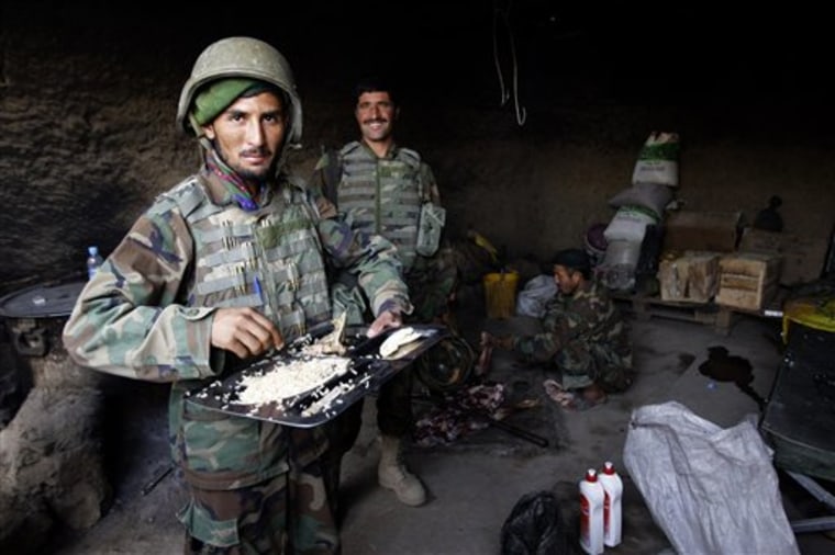 In this photograph taken Sept. 10, 2010, Afghan soldiers eat a meal at their outpost beside the Pir Mohammed school, in Zhari district,  Kandahar province, south of Kabul, Afghanistan. Over the last six months, U.S. troops have wrested the school away from insurgents. They've hired Afghan contractors to rebuild it, and lost blood defending it. But the tiny school has yet to open, and nobody's quite sure when it will. (AP Photo/Adil Bradlow)